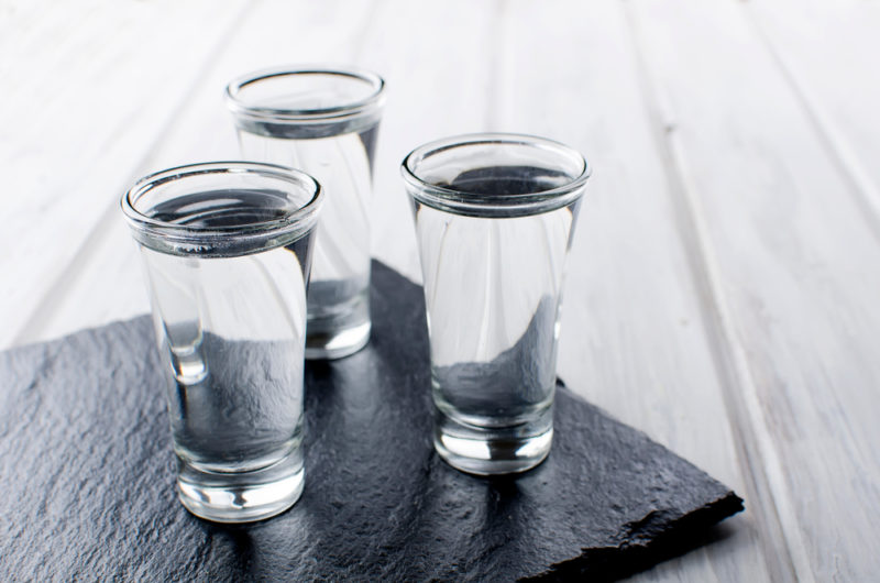 Three shot glasses of tequila on a black slate