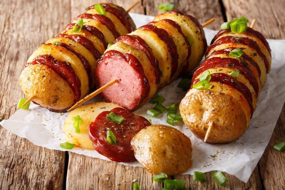 Three skewers that contain alternating pieces of sausage and potatoes