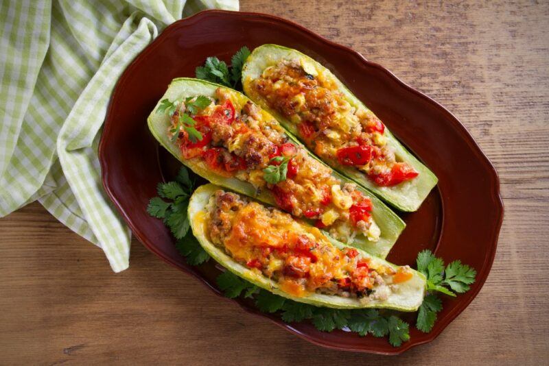 Three sliced zucchinis that have been stuffed and cooked