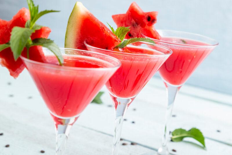 Three watermelon martinis on a table, each using a piece of watermelon as a garnish