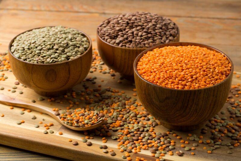 Three wooden bowls with different colored lentils