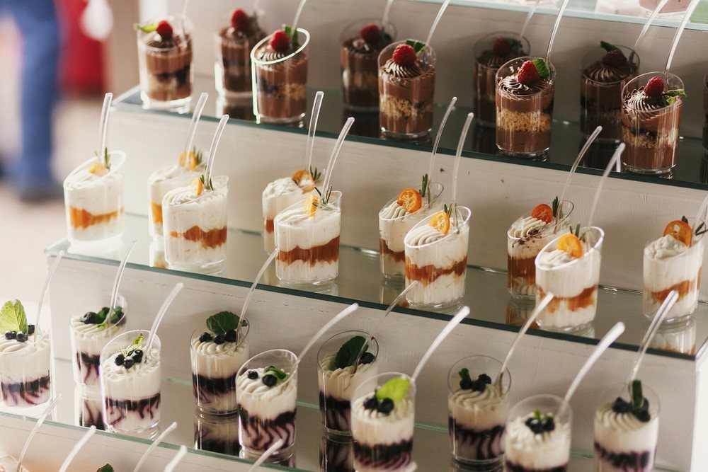 A tiered stand with three different types of desserts in glasses