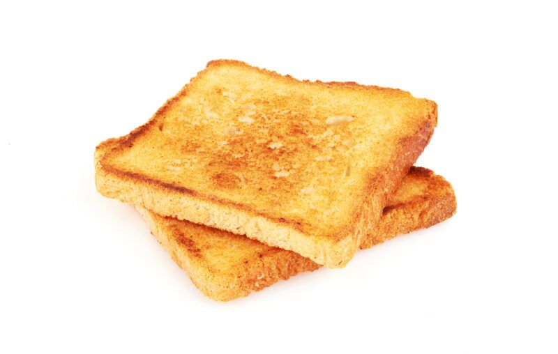 Two slices of toast made from white bread rest against a white surface.