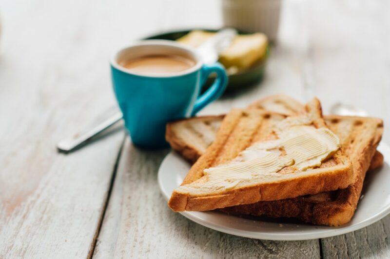 A plate with toast, next to a blue mug of coffee