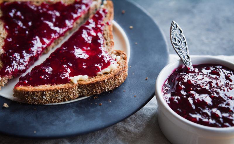 A blue plate with toast and jam, next to a pot of jam