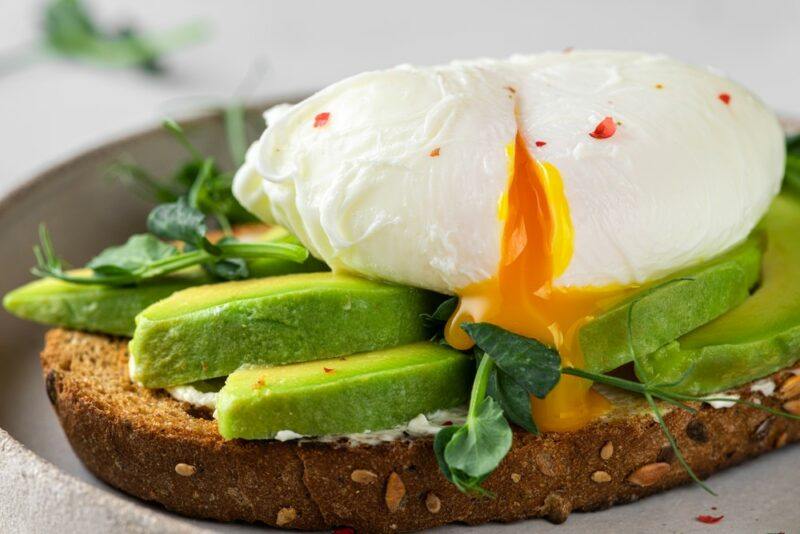 A piece of toast with sliced avocado and a perfectly poached egg