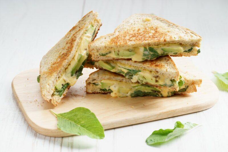 Three toasted sandwich halves on a wooden board