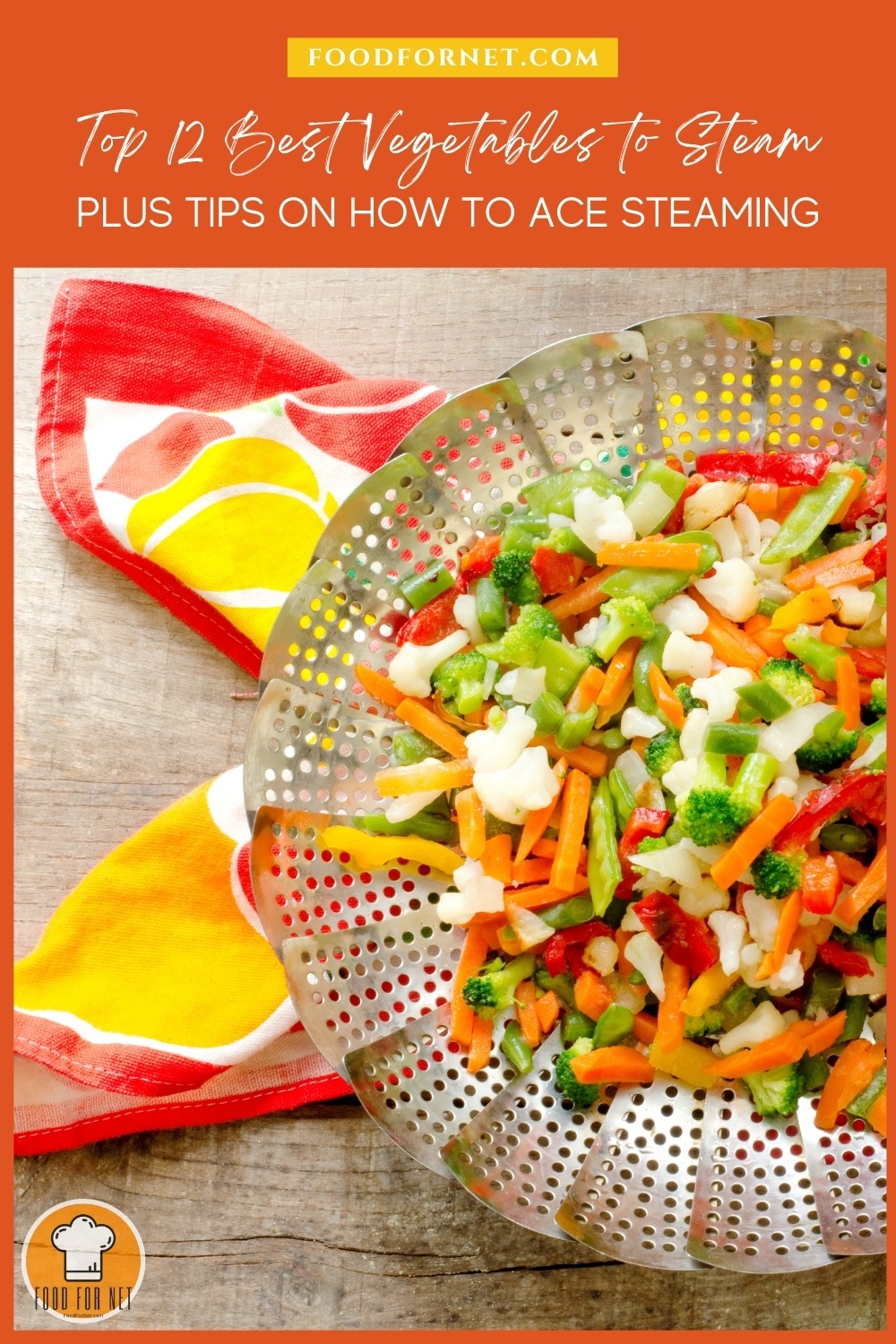 Best Vegetables to Steam. on a wooden surface is top view image of a collapsible steaming basket with steamed veggies including carrots, broccoli, cauliflower, red peppers, and peas, resting on top of a floral red, yellow, and white table napkin