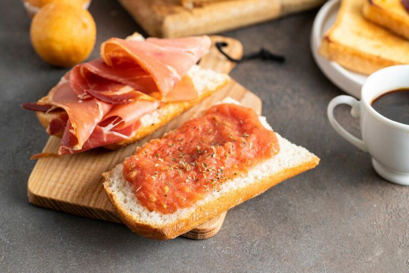 Two pieces of Spanish toast called tostadas, one with meat, the other with jam