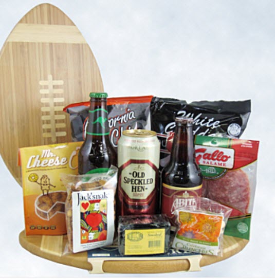 A football shaped cutting board with 3 beers and a selection of snacks on top. 