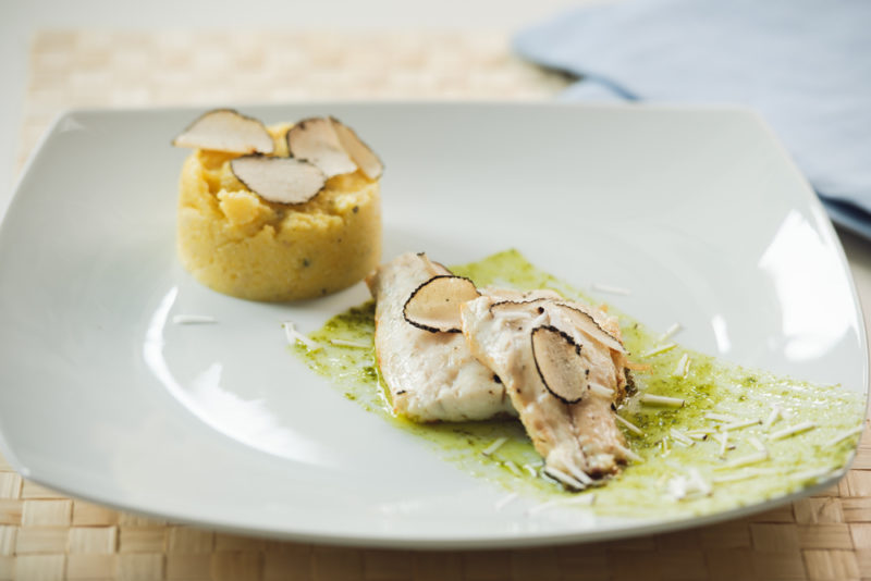 A white dish that contains polenta, white fish and white truffles