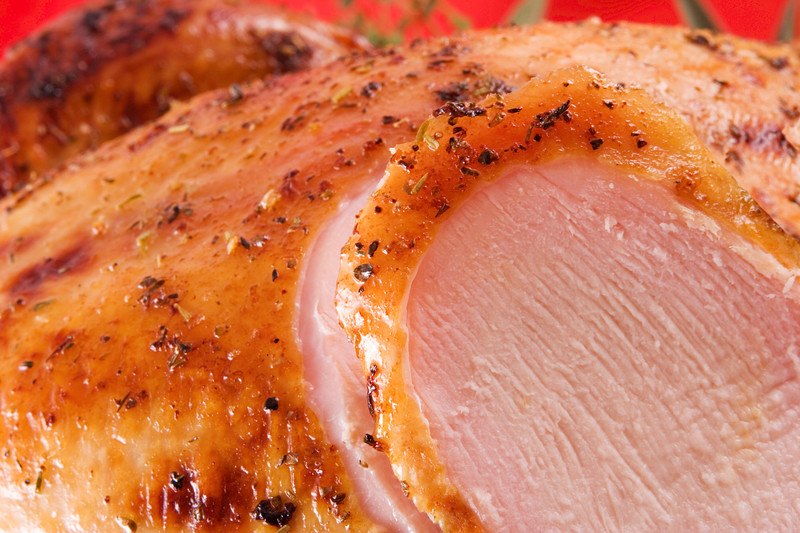 This photo shows a closeup of a roasted, partially sliced turkey breast.