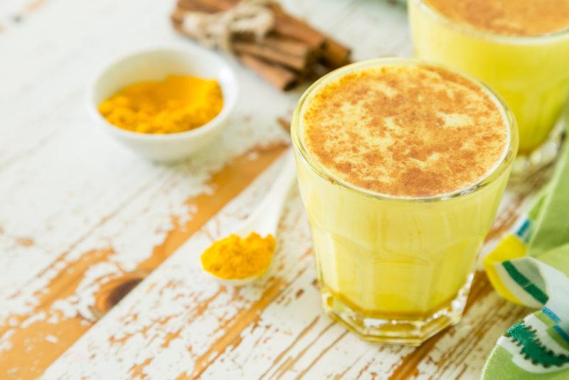 A glass of golden milk with turmeric and cinnamon on a table