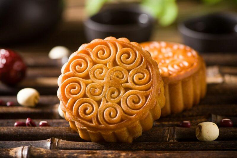 Two Chinese mooncakes on a table, one facing the camera so that the intricate pattern can be seen