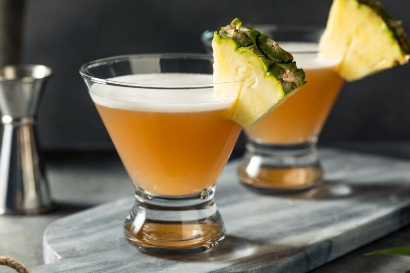 Two glasses containing French martini cocktails, with wedges of pineapple on the rim