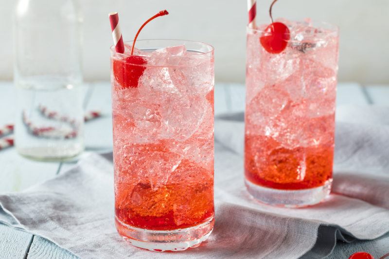 Two glasses of a Shirley Temple mocktail, both garnished with a cherry