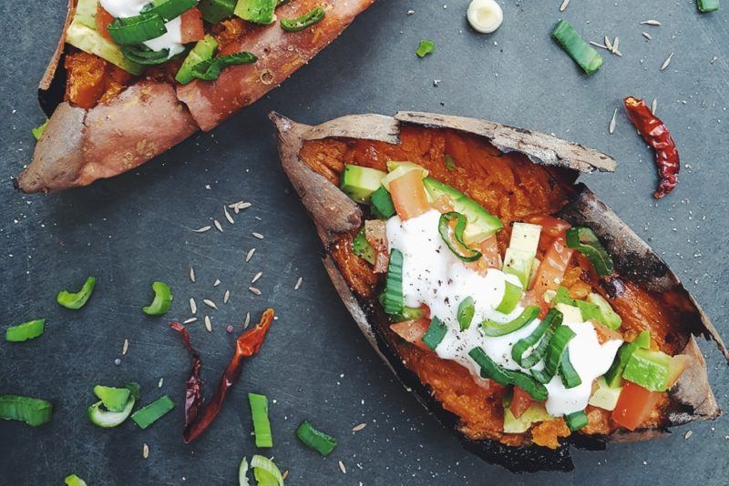 A baked sweet potato with sour cream and cucumbers