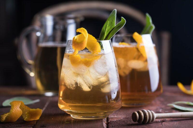 Two glasses containing a bee's tease cocktail with plenty of ice and a lemon twist