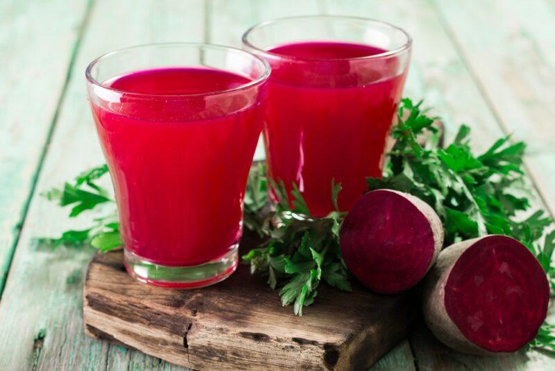 A white table with two glasses of beet juice next to cut beets