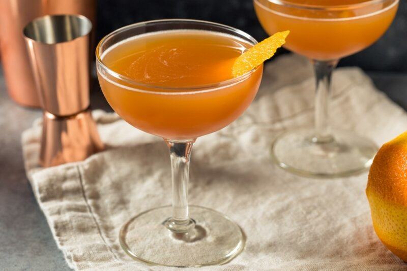 Two coupe glasses containing blood and orange cocktails on a cloth