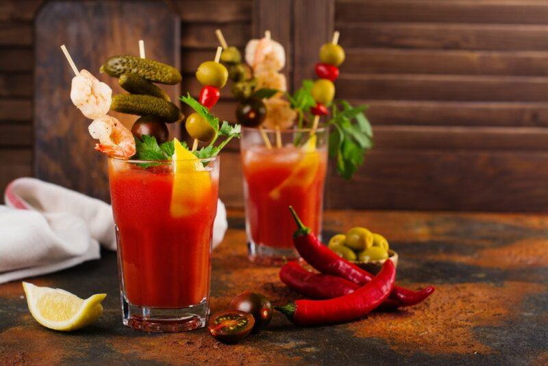 Two bloody Mary cocktails with an exceptional number of garnishes, including shrimp and olives