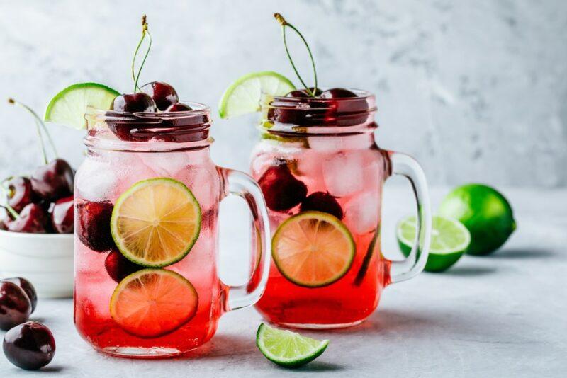 Two mason jars with handles, containing a cherry limeade cocktail