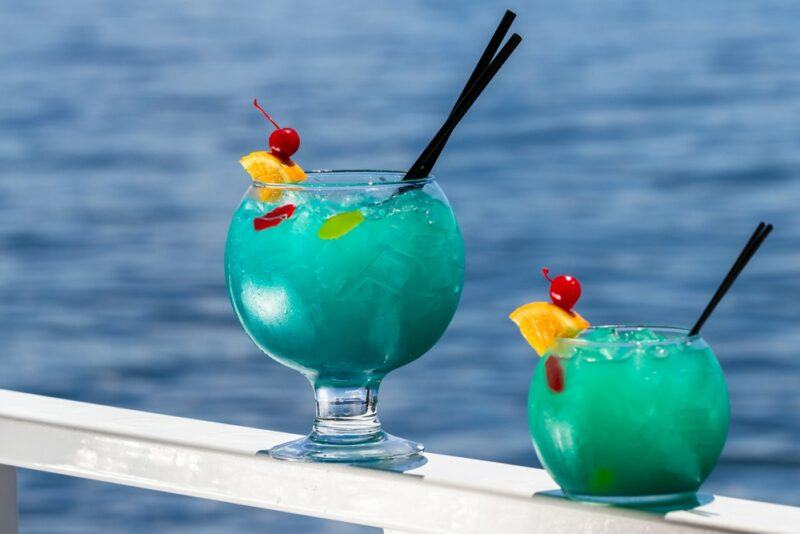 Two fishbowl like glasses containing a blue kool aid jungle juice cocktail