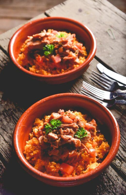 Two bowls of fiambrera, or some similar meal,on a wooden table