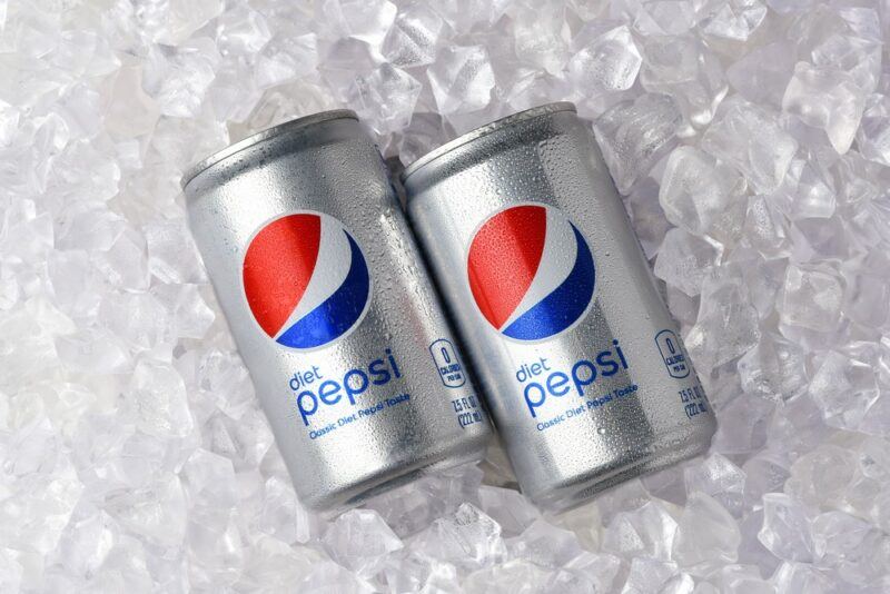 Two silver cans of diet Pepsi on a bed of ice