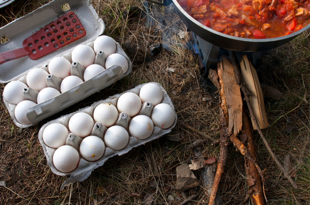 Two cartons of eggs next to a bowl of chili