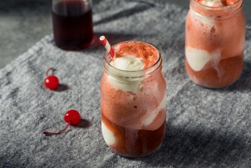 Two mason jars containing a cherry vanilla ice cream punch cocktail