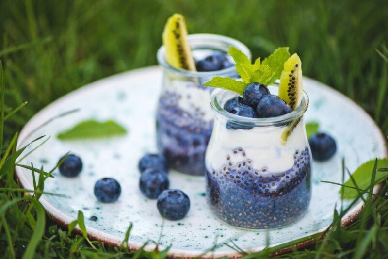 A tray with two jars of blueberry chia salad outside on the grass