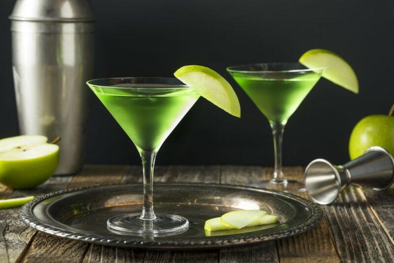 Two appletini cocktails in martini glasses with a wedge of apple each