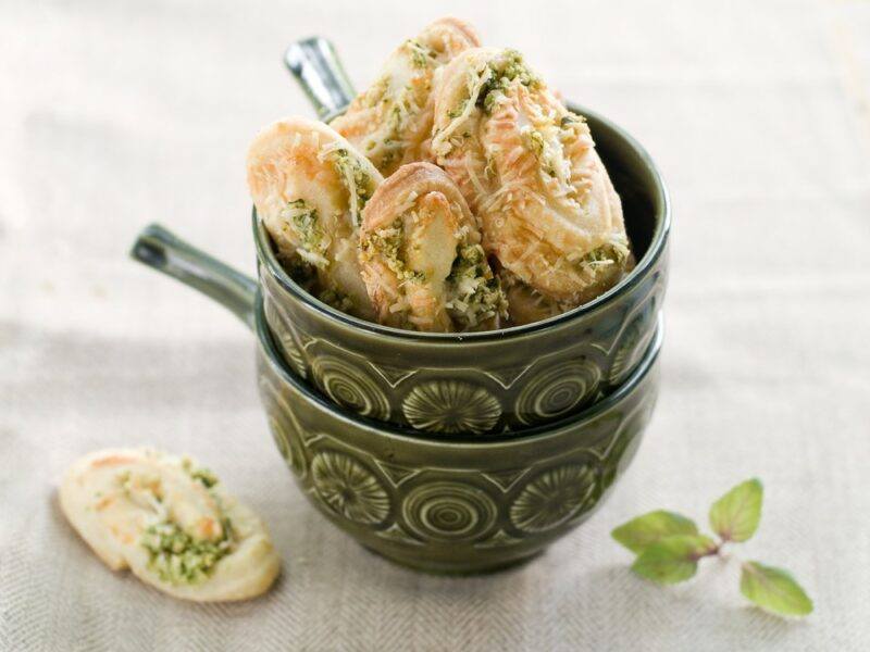 Two bowls stacked into each other, with the top one containing many pesto cookies