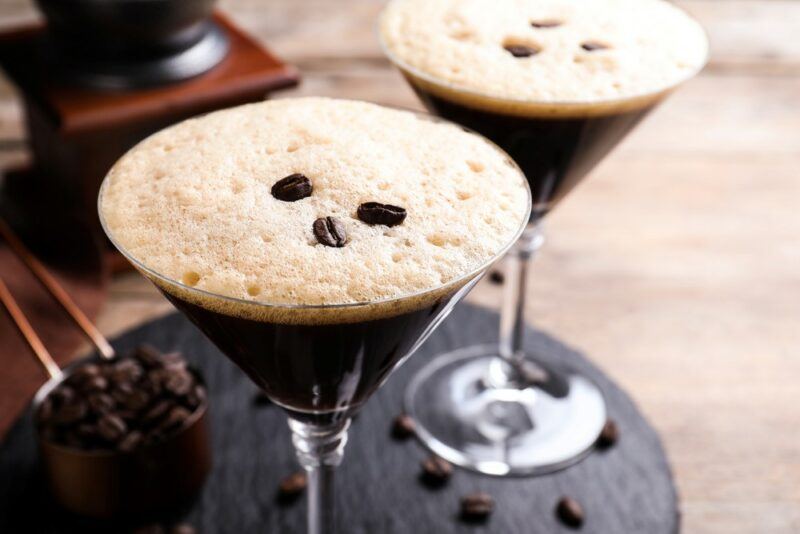 Two martini glasses containing an espresso martini with coffee beans on the top