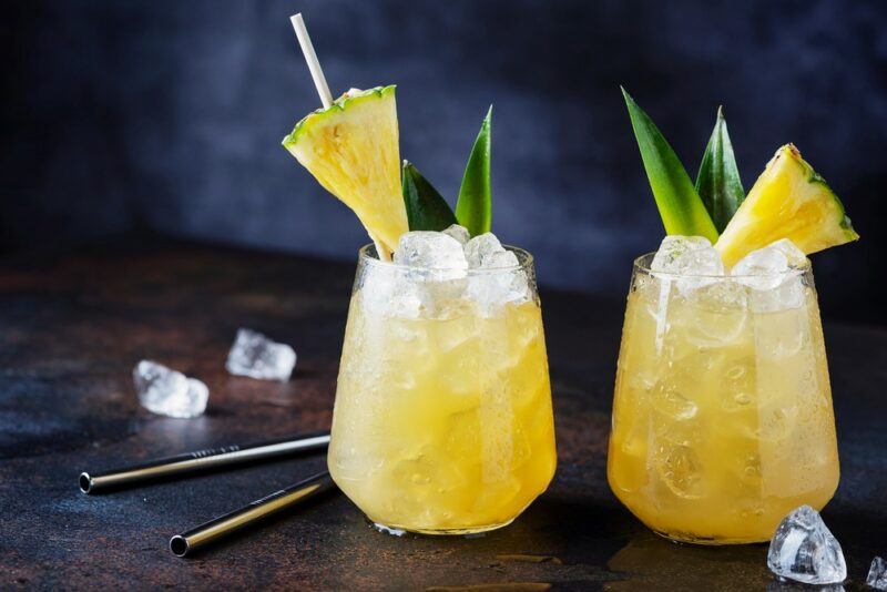 Two glasses containing a Fire Away cocktail with crushed ice and pineapple