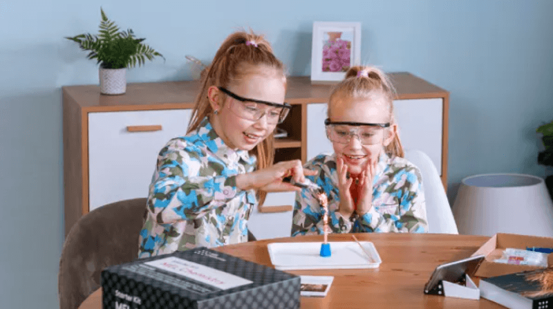 Two girls sitting at table working on a science project