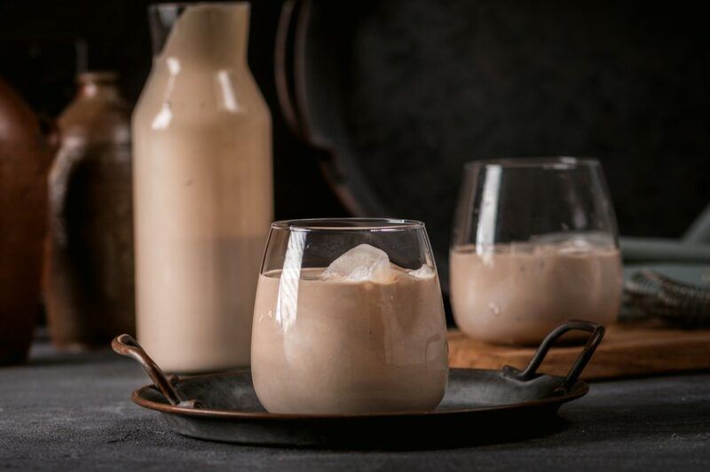 Two glasses of white chocolate liqueur with ice, next to a bottle of the liqueur