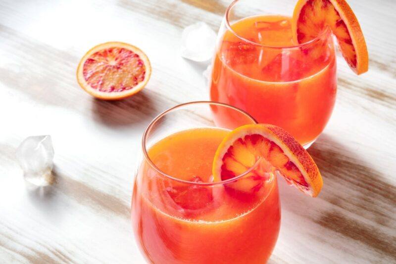 Two glasses of a Port Royal punch cocktail, with blood orange pieces as a garnish