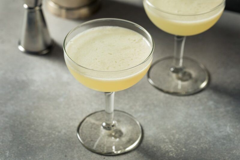 A table with two coupe glasses containing a corpse reviver no. 2 cocktail