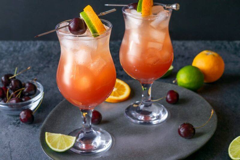 Two glasses with a hurricane cocktail and ice, with fruit as a garnish