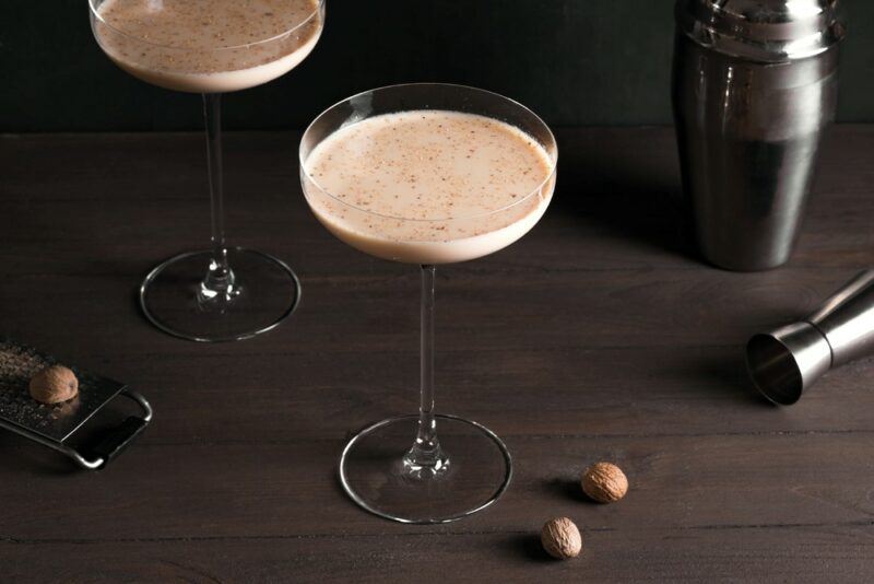 A dark wooden table with two glasses of a cocktail called ponche de algarrobina