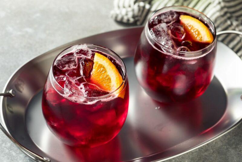 A metal tray with two glasses of a red wine spritzer with citrus as a garnish