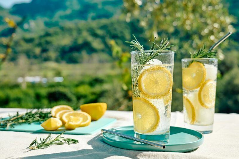 Two tall glasses containing sparkling water and lemons