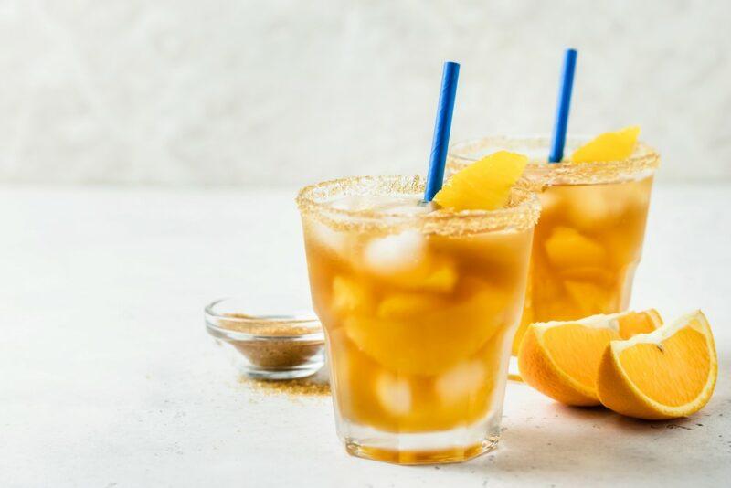 Two glasses containing Fireball orange sweet tea cocktails with straws