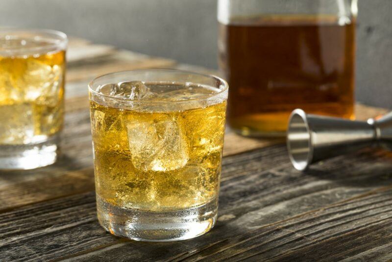 Two glasses containing a Scotch and soda cocktail, next to a jigger and a bottle of Scotch