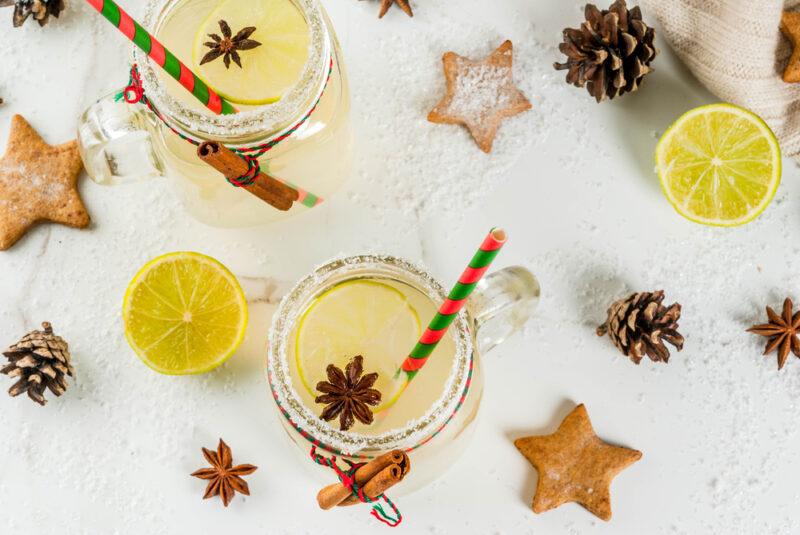 Two mason jars filled with a hot Christmas mule cocktail, with cookies, lemons, pine cones, and star anise on the table