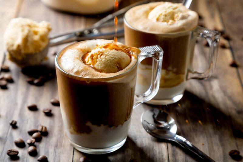 A wooden table with Guinness affogato cocktails, each with ice cream, next to coffee beans and a scoop of ice cream