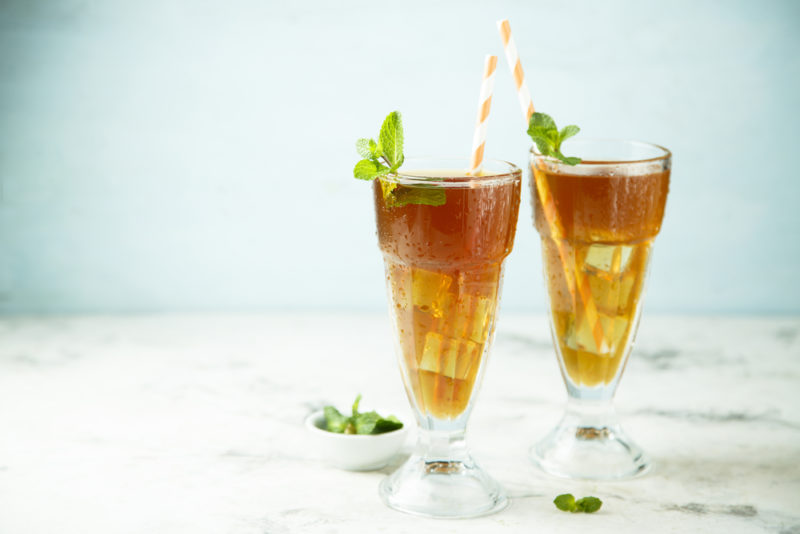 Two glasses of a John Daly cocktail on a table against a blue background