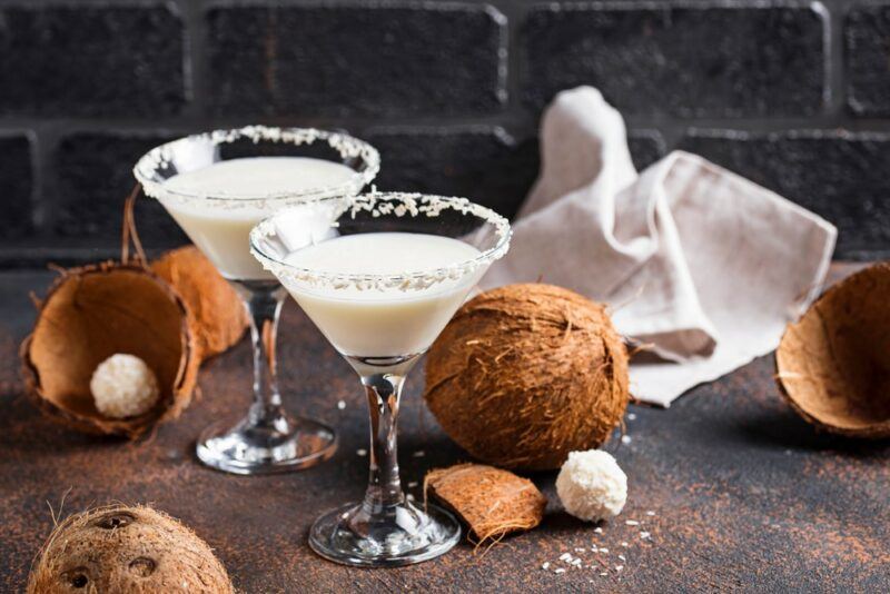 Two glasses of a bourbon coconut milk cocktail, surrounded by coconuts